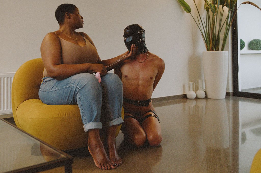 Cambridge Dominatrix with kneeling masked submissive during training session